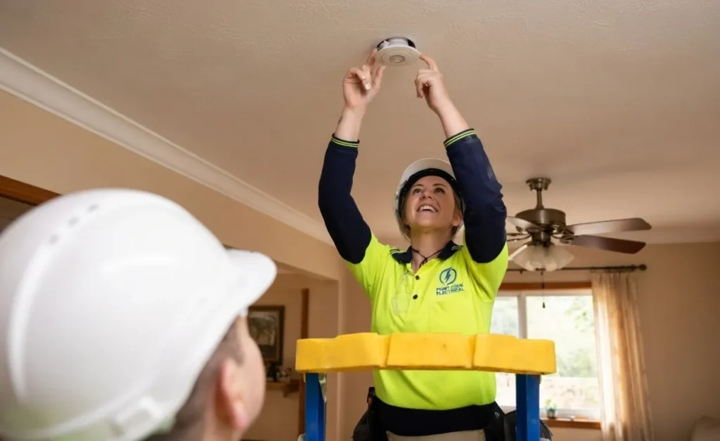 Electrician installing a ceiling smoke alarm